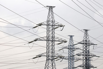 High voltage towers with electrical wires on cloudy sky background. Electricity transmission lines, electric power station