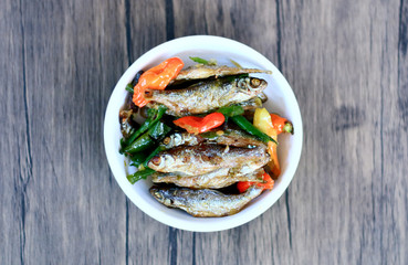 Sauteed anchovy fish or tumis ikan bilis on wood background. 