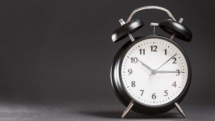 Retro black alarm clock against black background