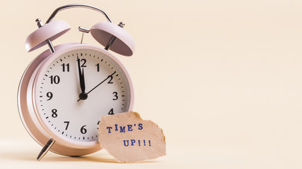 Times up text on torn paper near the alarm clock against beige background