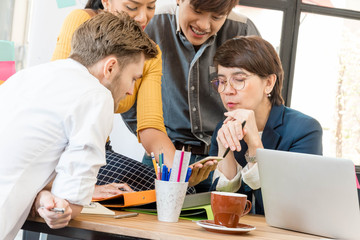 Group of four casual business meeting to discuss ideas and computer laptop on table in office. creative worker brainstorm together in office, new style of workspace, relax scene of people in office
