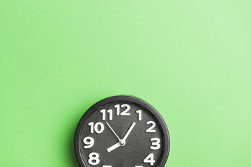 Circular black clock on green wall backdrop