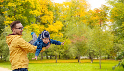 family, childhood and fatherhood concept - happy father and little son playing and having fun outdoors over autumn park background