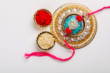 Indian festival Raksha Bandhan , Rakhi with rice grains, kumkum on Decorative plate , A traditional Indian wrist band which is a symbol of love between Brothers and Sisters