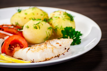 Fried fish with potatoes on wooden table
