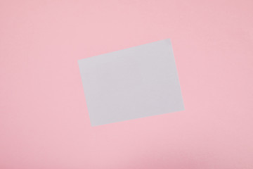 Fototapeta na wymiar top view of blank white card on pink background