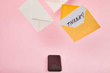 yellow envelope with white card with thanks lettering near letters and smartphone with blank screen...