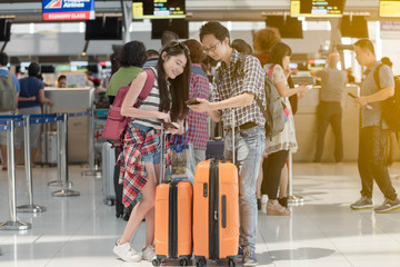 Man and woman traveller checking flight in smartphone at the airport terminal.