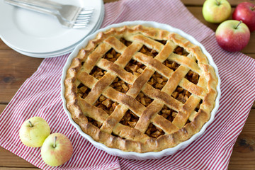 food, culinary and baking concept - apple pie and kitchen towel on wooden table