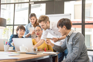 Group of five casual business meeting to discuss ideas and laptop on table in office.