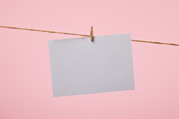 white empty card hanging on rope isolated on pink