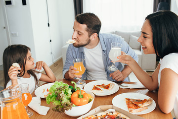 happy multi ethnic family, mother, father and daughter during dinner.Eating delicious pizza with family