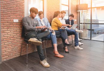 Group of five casual business meeting to discuss ideas and laptop on table in office.