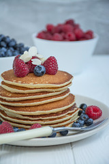 Classic American pancakes with fresh berry on a blue wooden background. Pancakes with fruit. Summer homemade breakfast.