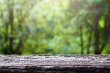 Fototapeta premium old wooden table top on green blurred abstract background from foliage background. Ready used us display or montage products design