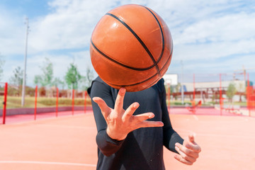 Close up of attractive man holding basket ball. Ball is on focus and foreground.