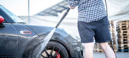 Mann putzt sein Auto mit dem Kärcher Hochdruckreiniger