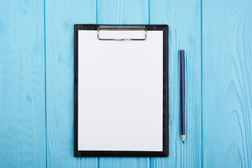 Planner on the blue wooden working table. Blank white paper on working desk
