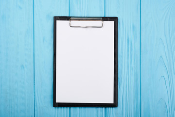 Planner on the blue wooden working table. Blank white paper on working desk