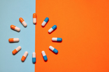 Blue and orange vitamins on a colored background