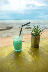 Icy blue milk shake on yellow table.