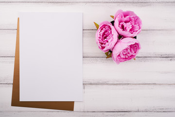 White paper on the wooden desk with flower and scissors