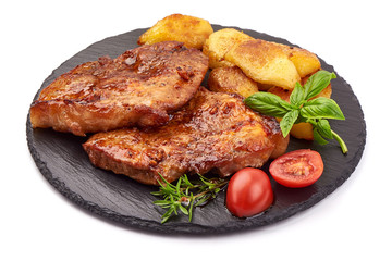 Baked juicy pork steak with fried potatoes on a stone plate, isolated on white background