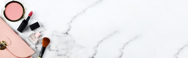 Top view of woman's light pink cosmetics bag on white marble background with pink cheek blush, pink...