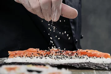 Crédence de cuisine en verre imprimé Bar à sushi Gros plan des mains du cuisinier. Un chef masculin prépare des sushis et des petits pains à base de riz, de poisson rouge et d& 39 avocat. Gants blancs.