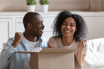 African spouses sit on couch with cardboard box feels happy