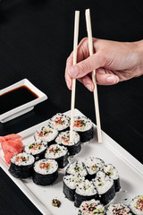Set of rolls with red fish and ginger. Table setting. Black background. Ingredients for cooking Japanese cuisine.