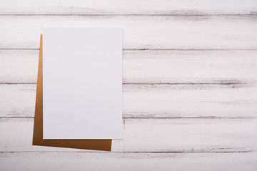 White paper on the wooden desk with flower and scissors