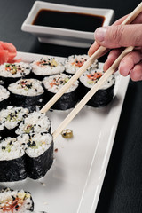 Set of rolls with red fish and ginger. Table setting. Black background. Ingredients for cooking Japanese cuisine.