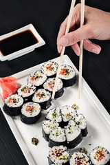 Set of rolls with red fish and ginger. Table setting. Black background. Ingredients for cooking Japanese cuisine.