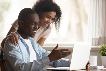African spouses look at computer screen having fun at home