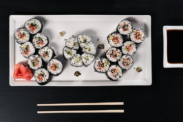 Set of rolls with red fish and ginger. Table setting. Black background.
