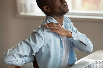 Cropped image african guy touch shoulder suffers from painful sensations