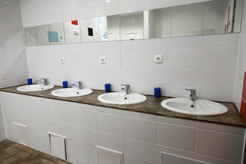 Empty restroom public men bathroom interior with washing hand sinks. Mirror with hand basin in clean toilet.