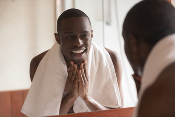 African man looking in mirror cleaning face after shaving