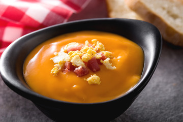 Typical Spanish salmorejo cream with ham and egg on gray background