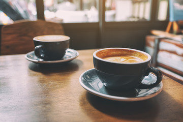Closeup image of two blue cups of hot latte coffee on vintage wooden table in cafe