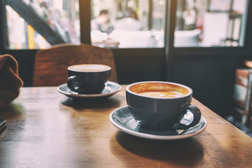 Closeup image of two blue cups of hot latte coffee on vintage wooden table in cafe