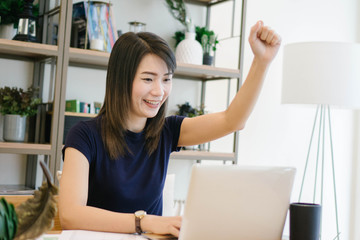 Happy excited successful asian woman while she using computer labtop at her apartment,Lifestyle Concept