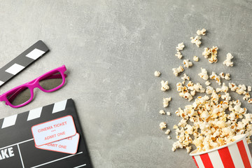 Clapperboard, tickets, 3d glasses and bucket with popcorn on grey background, top view
