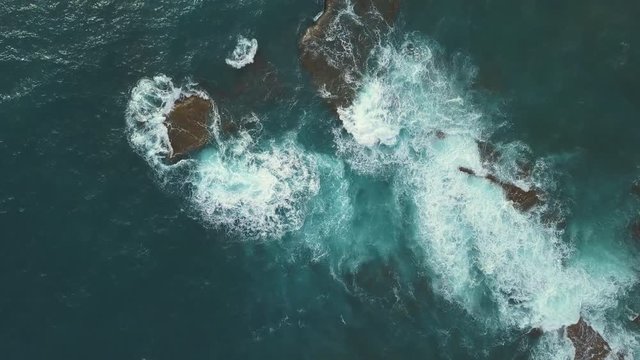 Aerial View of green foaming ocean waves crushing against the rocks. Indonesia, Bali