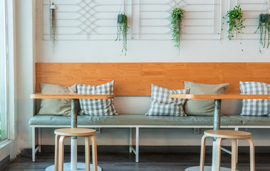 Coffee house interior with wooden table and chairs decorated with hanging bush. Minimal style decoraion.