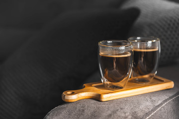 Two cups of espresso on a wooden tray, on the sofa in a cozy home environment