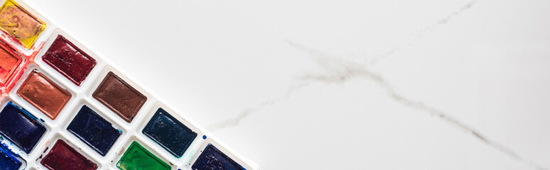 watercolor paint palette on marble white surface with copy space, panoramic shot