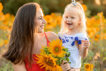Mother and daughter laughing in the field with sunflowers