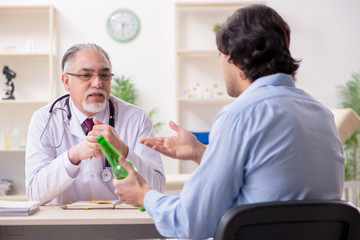 Obraz premium Young male alcoholic visiting old doctor